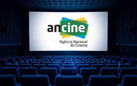 Marca da ANCINE projetada na tela de uma sala de cinema vazia